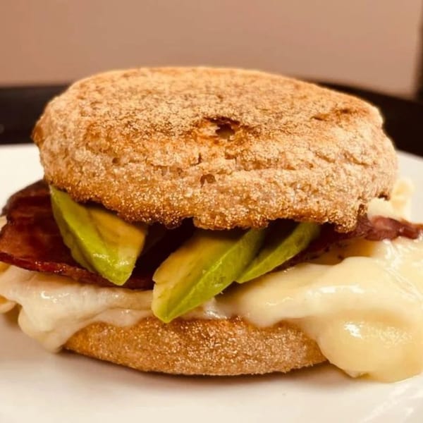 A Route 12 Cafe breakfast sandwich with bacon, avocado, and melted cheese on an English muffin.