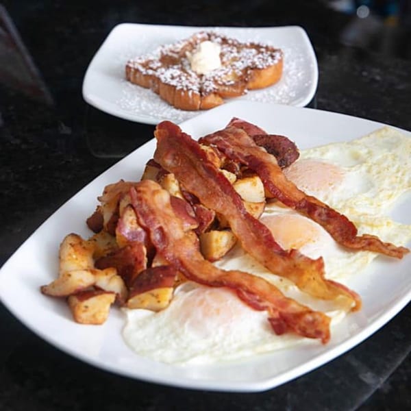A Route 12 Cafe breakfast with bacon, eggs, home fries, and French toast with powdered sugar.