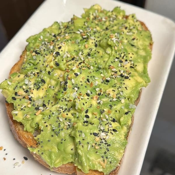 Avocado toast topped with everything bagel seasoning on a white plate at Route 12 Cafe.