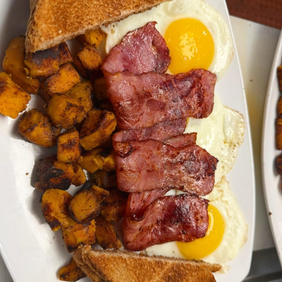 Route 12 Cafe's breakfast plate with crispy bacon, fried eggs, roasted sweet potatoes, and toast.